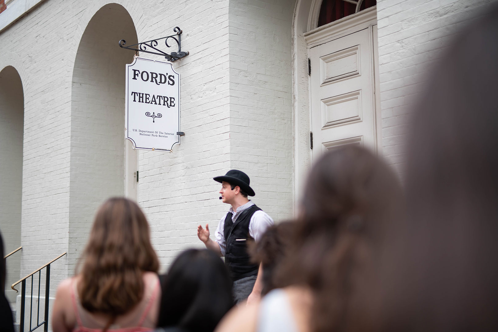 A group of young adults outside of Ford's Theatre watch a guide dressed as 1860s Washington Detective James McDevitt. 