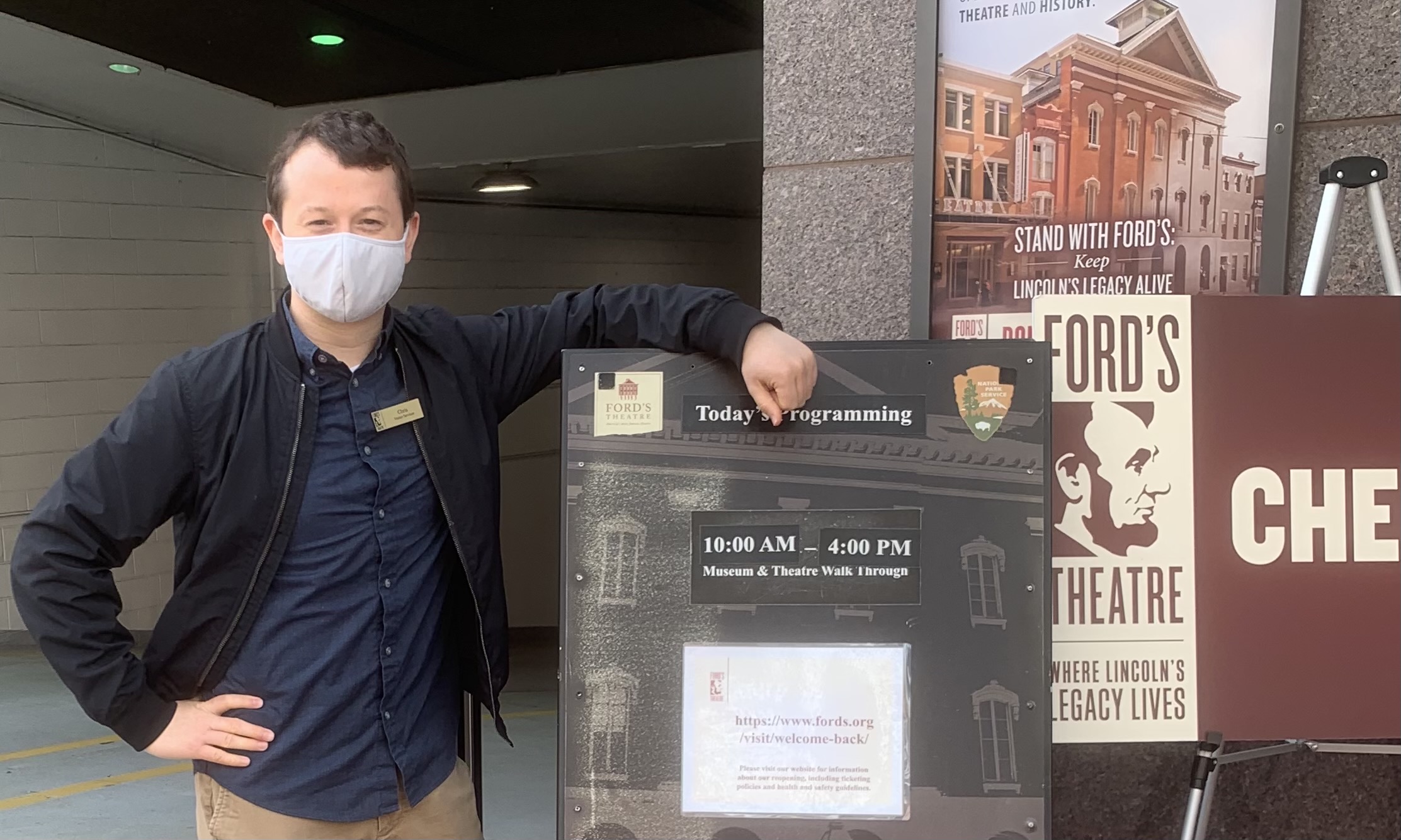 Chris stands outside of the Ford's Theatre entrance with the board where daytime entry details are posted.